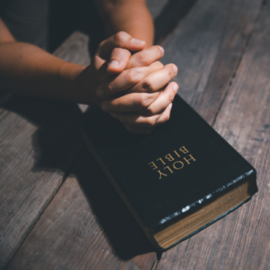 hands clasped on Bible